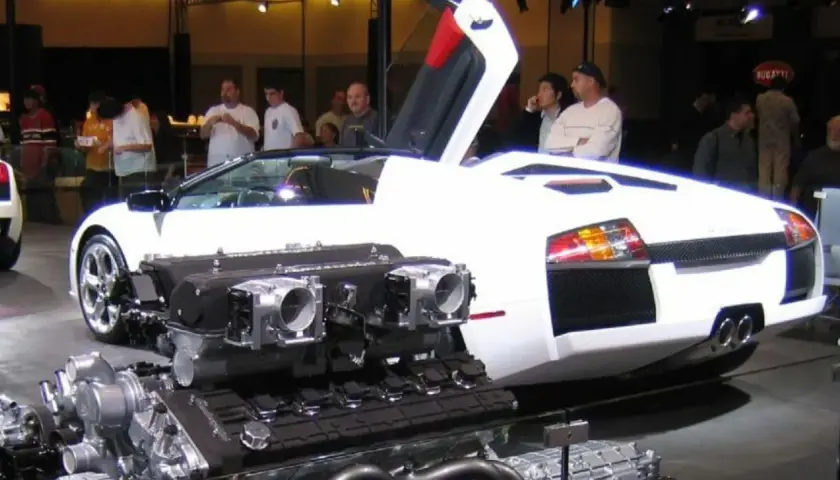 Biały Lamborghini Murcielago z otwartymi drzwiami i wyeksponowanym potężnym silnikiem V12.
