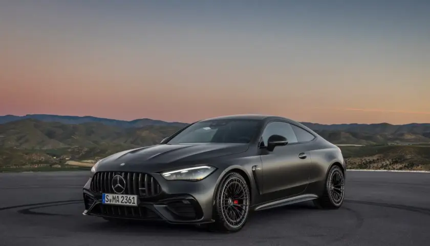 Mroczny Mercedes-AMG GT Coupe na tle zachodzącego słońca i pagórków.