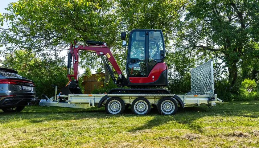 Mini koparka na przyczepie, gotowa do transportu. Posiadanie prawa jazdy na przyczepę to klucz do samodzielnego przewożenia sprzętu.