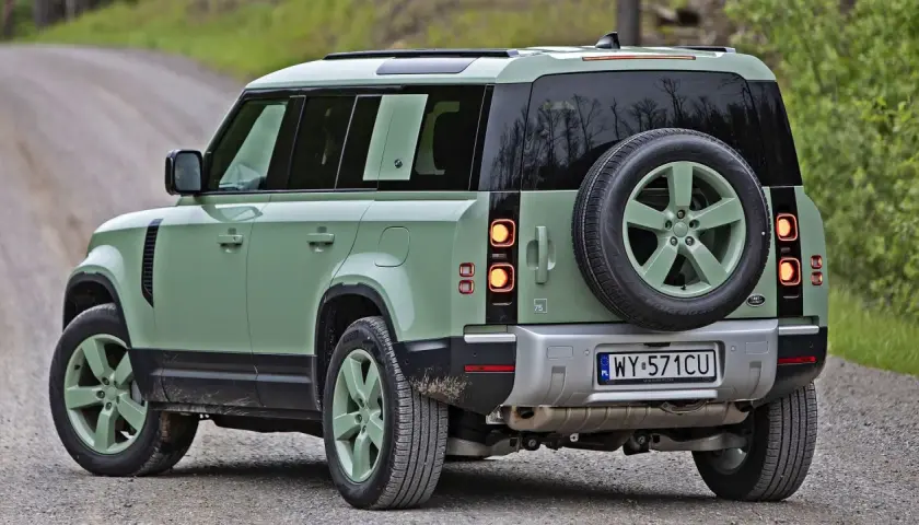 Zielony Land Rover Defender na szutrowej drodze, gotowy na przygodę.