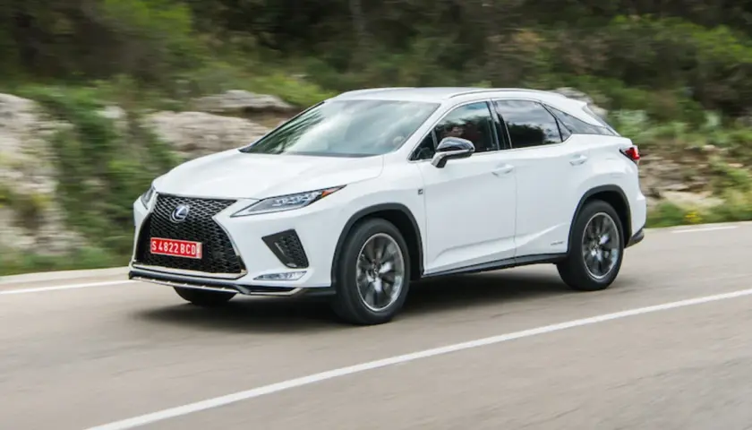 Biały Lexus RX 300 pędzi po krętej drodze wśród zielonych wzgórz.
