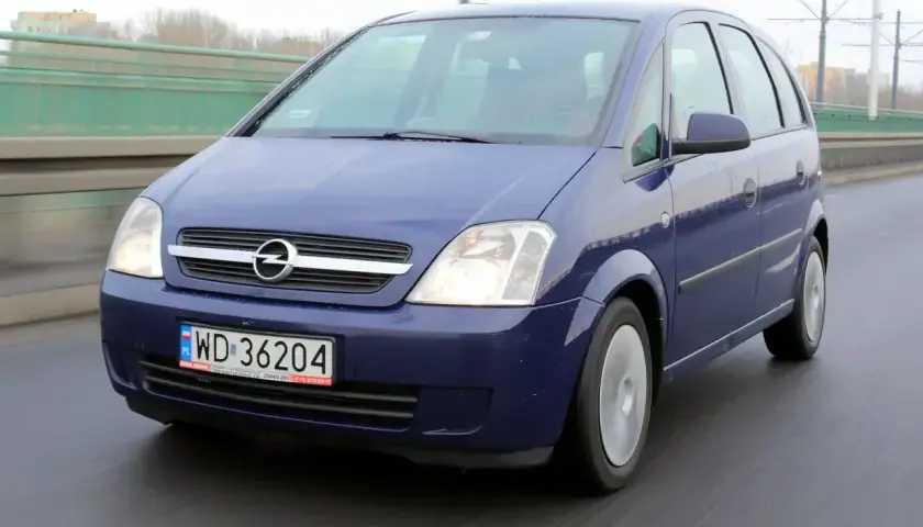 Niebieski Opel Meriva 1.6 benzyna jedzie po mokrej drodze.