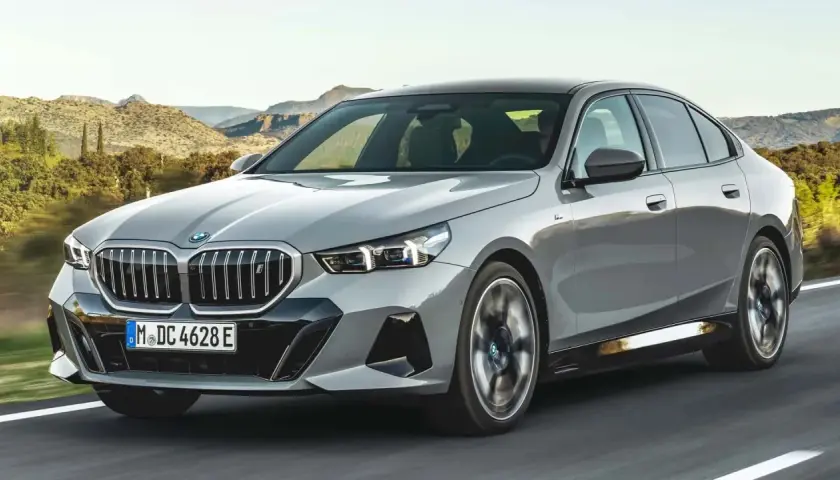 Szare BMW 540d jedzie po drodze na tle górskiego krajobrazu.