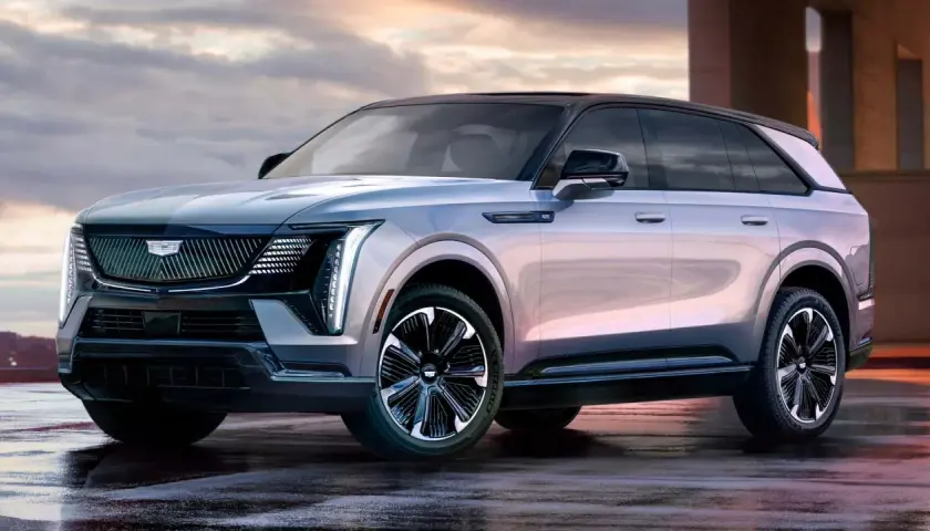 Elegancki Cadillac Escalade 2025 w kolorze srebrnym, z czarnym dachem i stylowymi felgami, prezentuje się imponująco na mokrej nawierzchni.