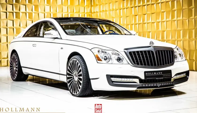 Biały Maybach 57 S z czarnym dachem i felgami, lśniącym na tle złotej, geometrycznej ściany.
