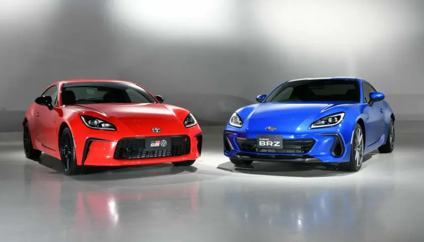 Dwa sportowe coupe, czerwona Toyota GR86 i niebieski Subaru BRZ, stoją obok siebie, gotowe do wyścigu.