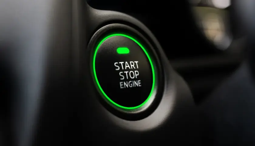Przycisk "START STOP ENGINE" z zieloną obwódką, gotowy do odpalenia auta.