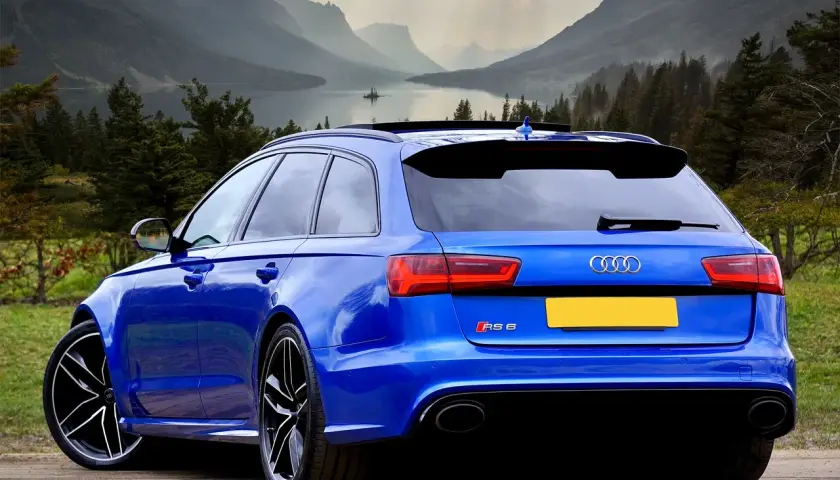 Niebieskie Audi RS6 z Niemiec, gotowe do rejestracji. Piękne góry i jezioro w tle.