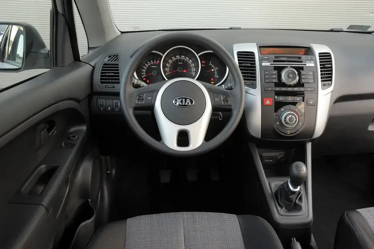 Wnętrze Kia Venga 1.4 benzyna: kierownica z logo Kia, deska rozdzielcza z radiem i nawiewami, dźwignia zmiany biegów.