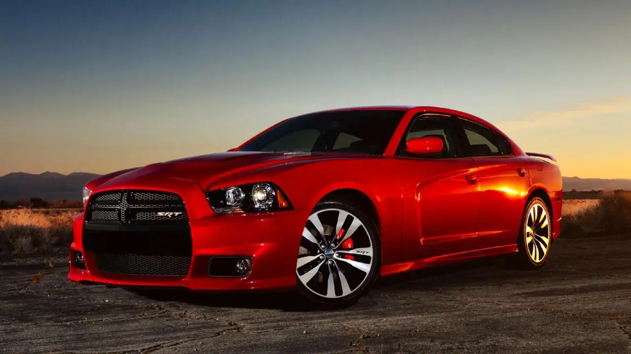 Czerwony Dodge Charger 5.7 Hemi SRT lśni w zachodzącym słońcu, gotowy do jazdy po pustynnej drodze.