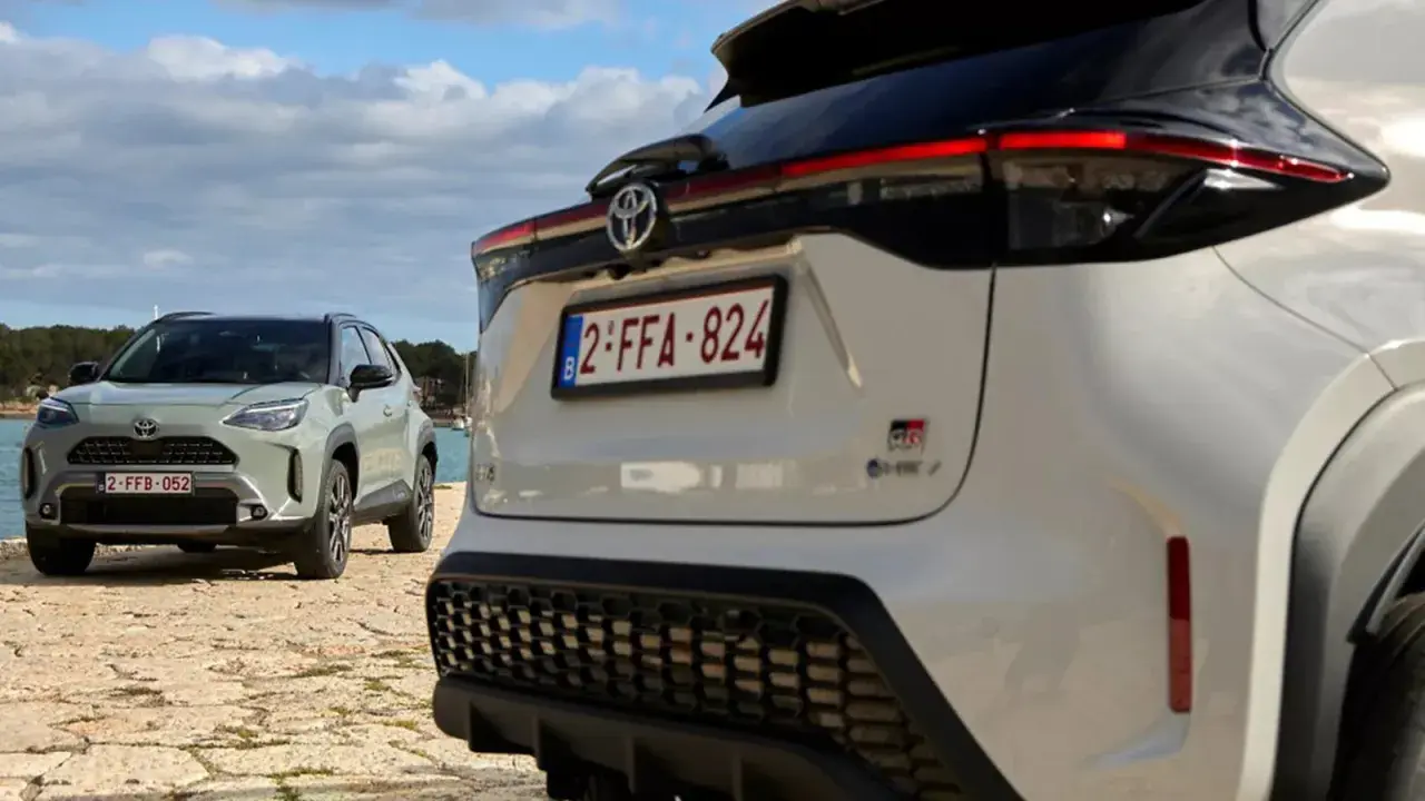 Dwa samochody Toyota, jeden biały, drugi zielony, stoją nad wodą. To świetny przykład, czym jest crossover – wszechstronny pojazd na każdą okazję.