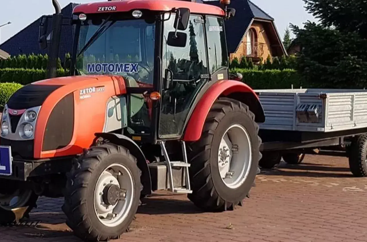 Czerwony Zetor z przyczepą, gotowy do pracy. Posiadanie prawa jazdy na traktor otwiera drogę do wielu możliwości.