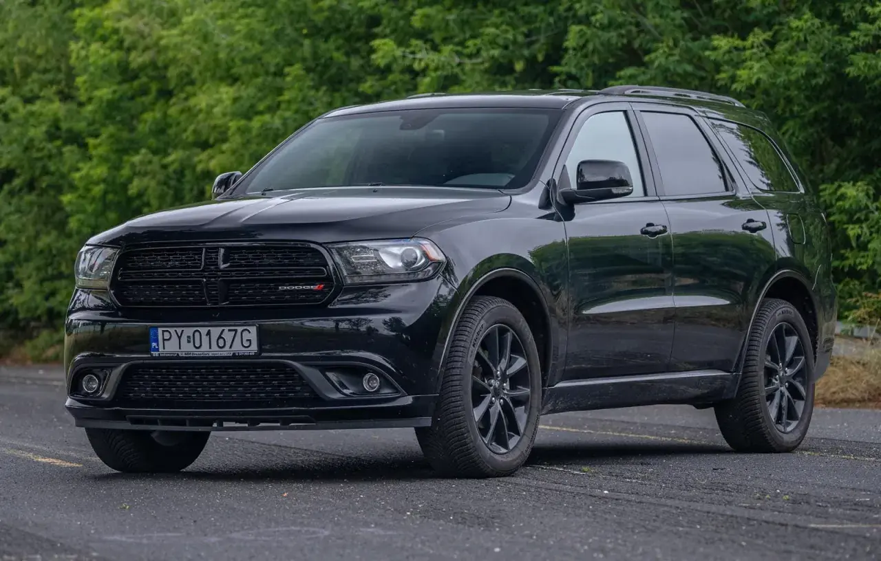 Czarny Dodge Durango 3.6, lśniący na tle zieleni. Potężny SUV gotowy na każdą podróż.