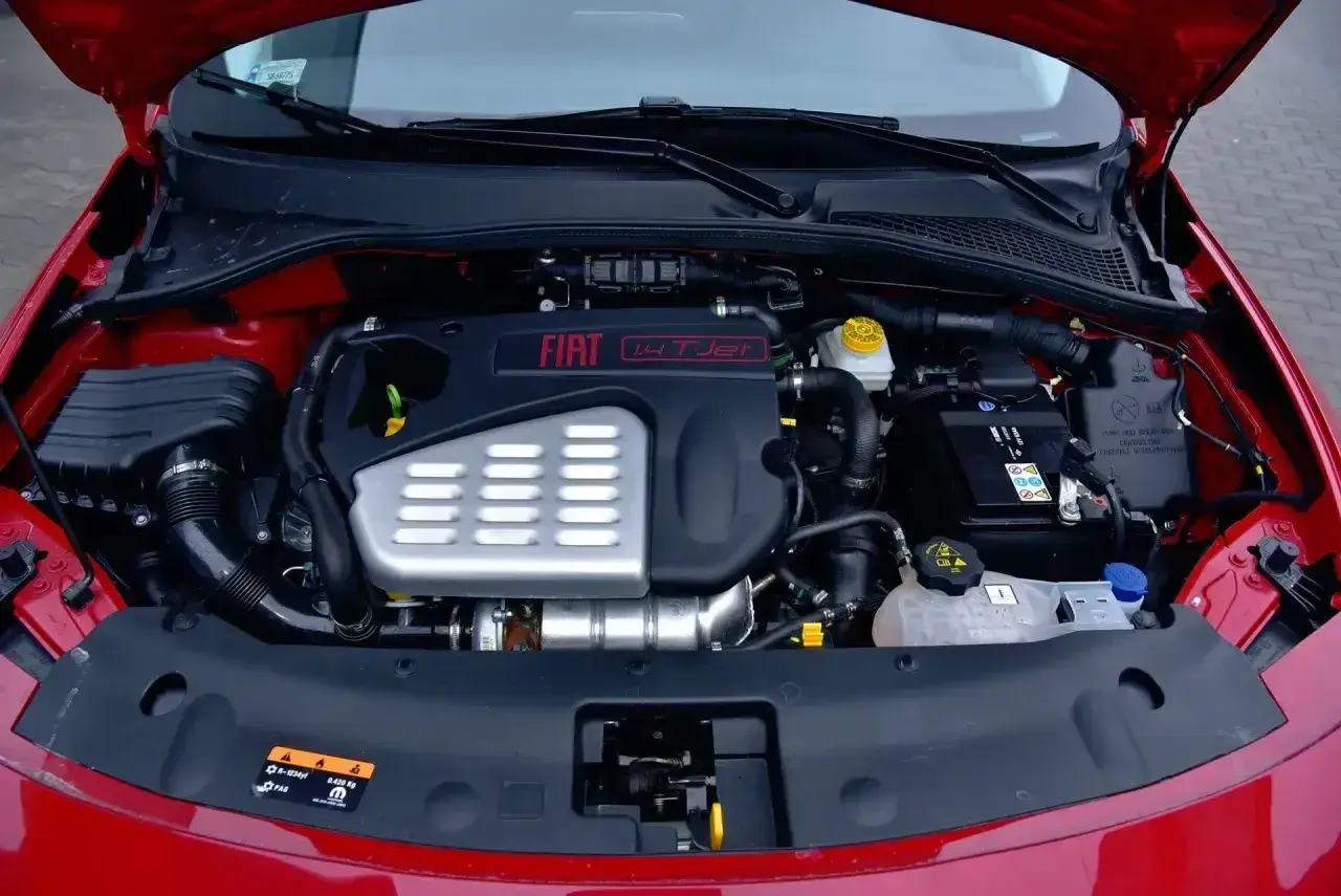Silnik fiat bravo 1.4 t-jet w komorze pod maską. Widoczny akumulator, układ dolotowy i osłona silnika.