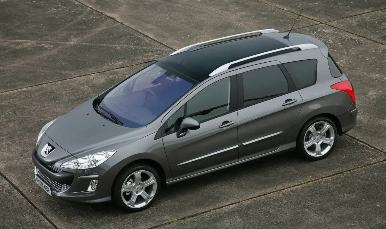 Szary Peugeot 308 1.6 HDi kombi z panoramicznym dachem stoi na betonowej nawierzchni.