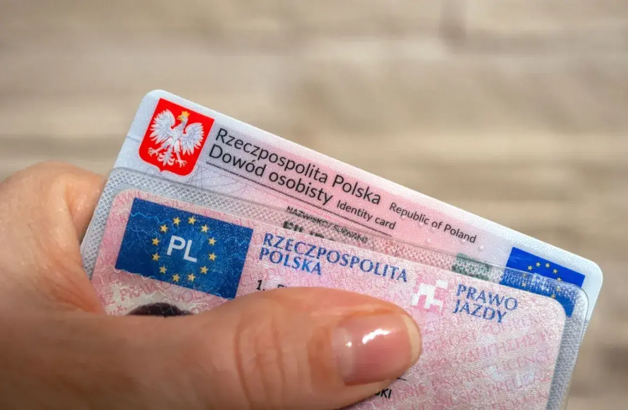 Dłoń trzyma polski dowód osobisty i prawo jazdy. To ważne dokumenty, które pozwalają na swobodne podróżowanie, a prawo jazdy bezterminowe daje spokój na lata.