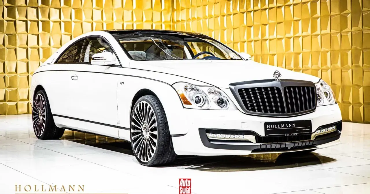 Biały Maybach 57 S z czarnym dachem i felgami, lśniącym na tle złotej, geometrycznej ściany.