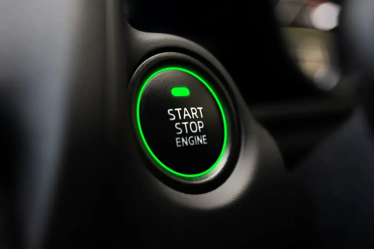 Przycisk "START STOP ENGINE" z zieloną obwódką, gotowy do odpalenia auta.