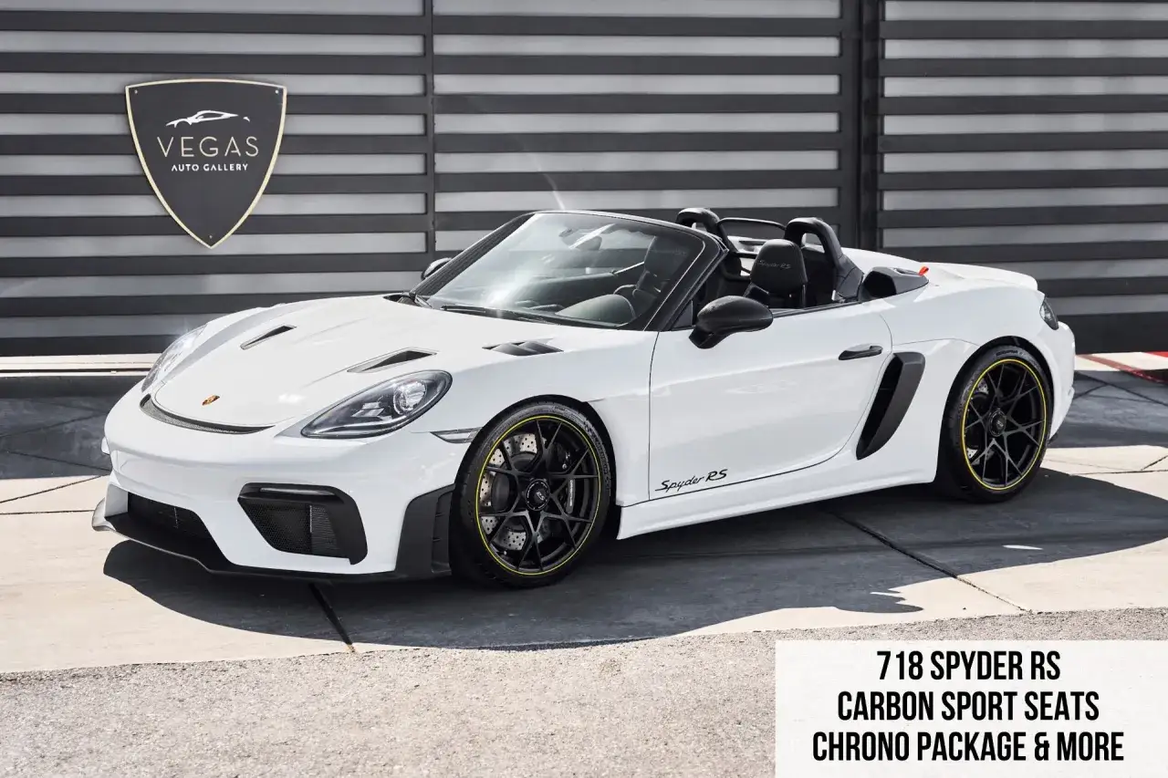 Biały Porsche Spyder RS z czarnymi felgami i żółtymi akcentami, zaparkowany przed galerią Vegas Auto Gallery.
