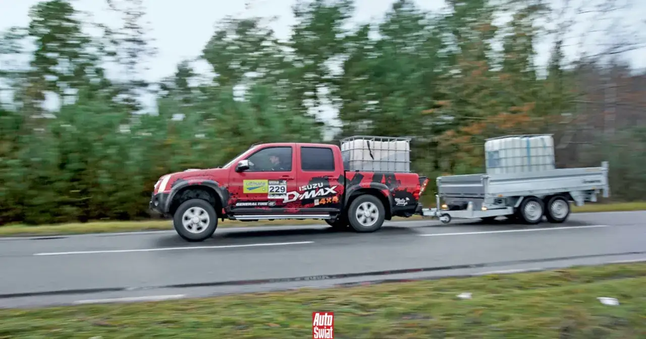 Czerwony Isuzu D-Max z przyczepą przewozi zbiorniki. Kierowca z prawem jazdy kategorii B+E poradziłby sobie z takim zestawem.