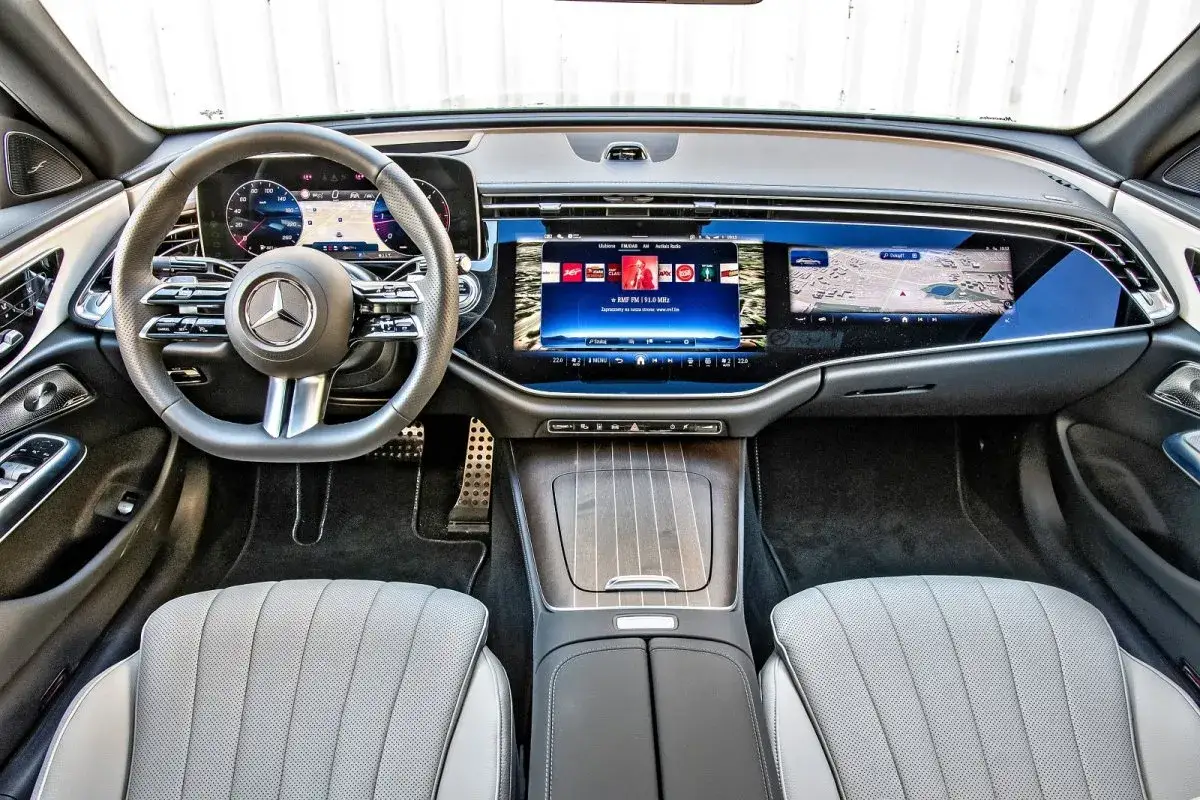 Wnętrze luksusowego mercedesa e220d z nowoczesnym ekranem MBUX, skórzaną tapicerką i kierownicą.