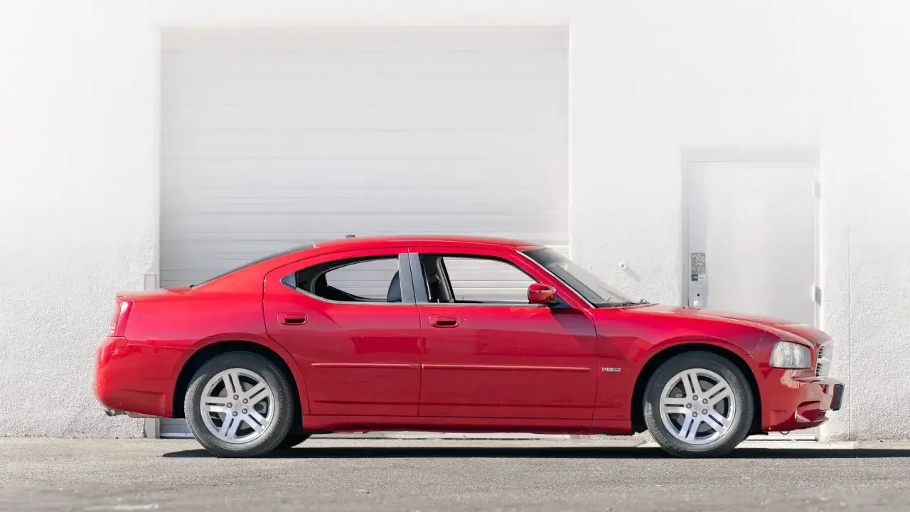 Czerwony Dodge Charger 5.7 Hemi stoi przed białą, nowoczesną ścianą.
