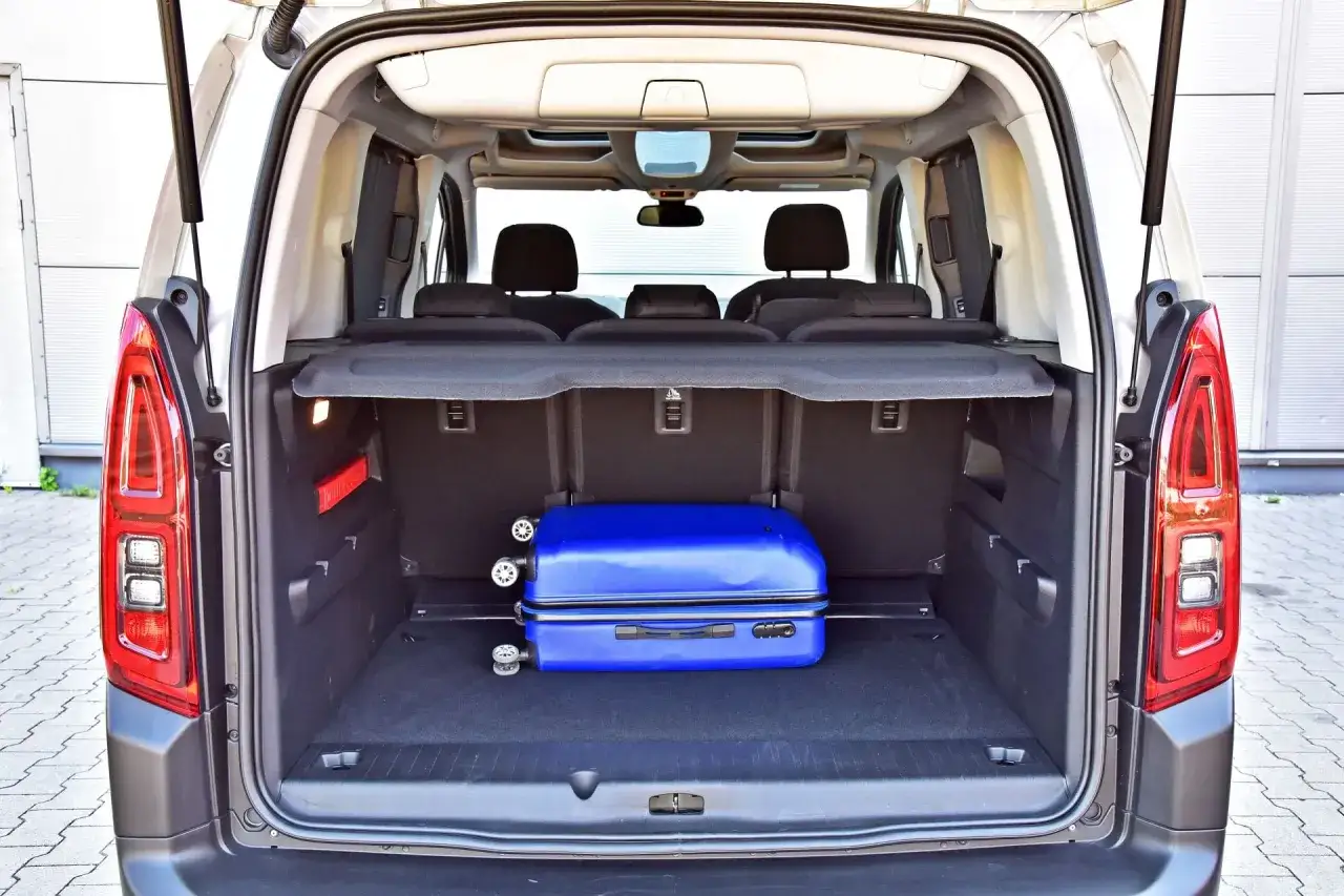 Bagażnik Citroen Berlingo 2 gotowy na podróż. W środku znajduje się niebieska walizka.