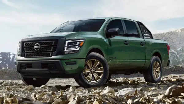 Zielony Nissan Titan z brązowymi felgami na kamienistym podłożu, gotowy na przygodę w górach.